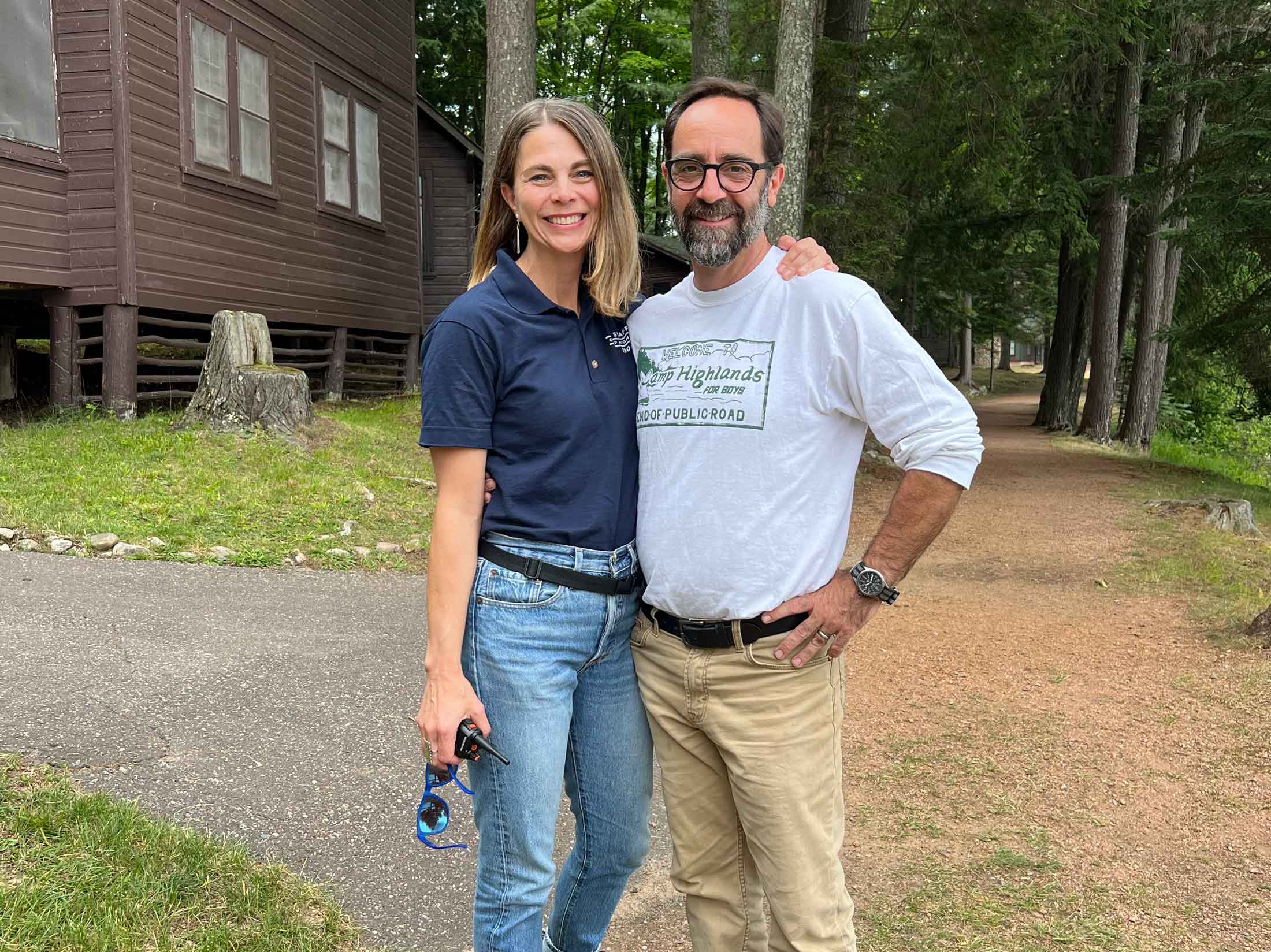 Camp directors standing together outside near a cabin, smiling at the camera